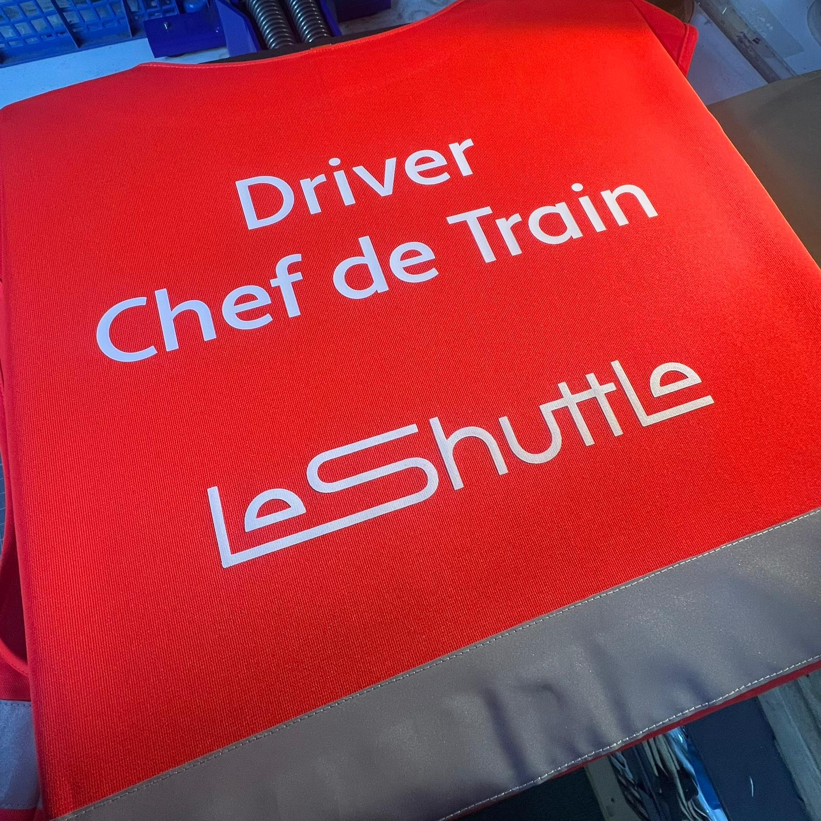 Red sign with 'Driver Chef de Train Le Shuttle' text on a gray press. Made at The Wrong End of Town in Dover, Kent.